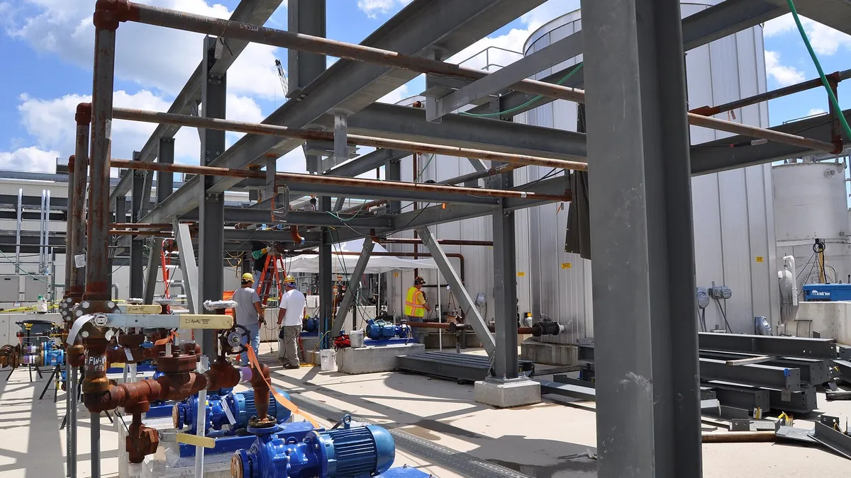 Installers working on pumps and pipe racks at an industrial site